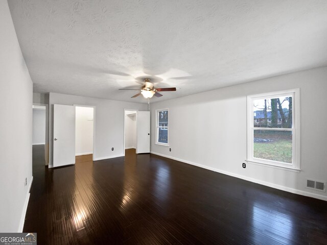 empty room with visible vents, baseboards, a textured ceiling, and dark wood-style flooring