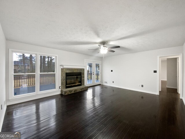 unfurnished living room with baseboards, a textured ceiling, dark wood-style floors, and a tile fireplace