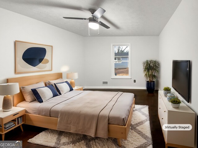 bedroom featuring a ceiling fan, wood finished floors, visible vents, baseboards, and a textured ceiling