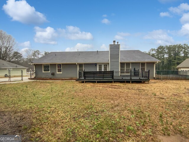 back of house with a gate, fence, a yard, a sunroom, and a chimney