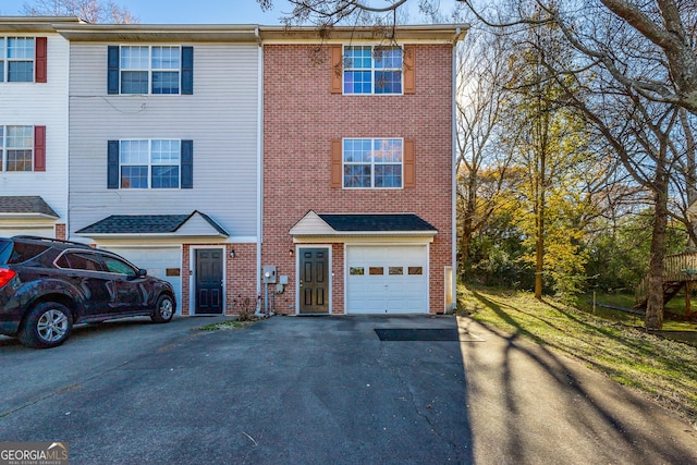 view of property featuring aphalt driveway, brick siding, and an attached garage