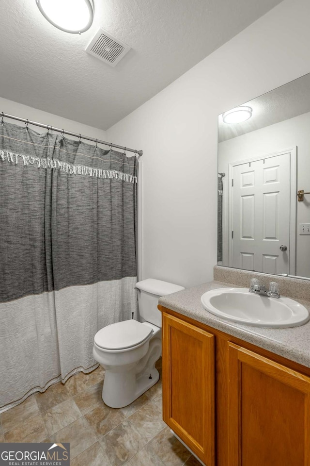 bathroom with visible vents, toilet, vanity, a shower with curtain, and a textured ceiling