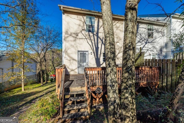 rear view of property featuring a deck, stairs, and fence