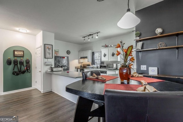 kitchen with a peninsula, dark wood-style flooring, freestanding refrigerator, a sink, and white cabinetry