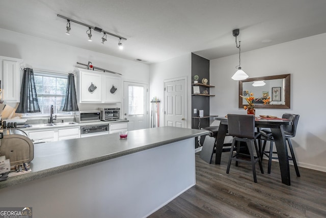 kitchen with a wealth of natural light, dark wood-type flooring, white cabinets, and a sink