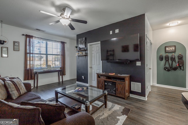 living area featuring a ceiling fan, wood finished floors, visible vents, and baseboards