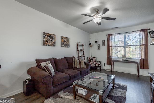 living area featuring dark wood-type flooring, baseboards, visible vents, and ceiling fan