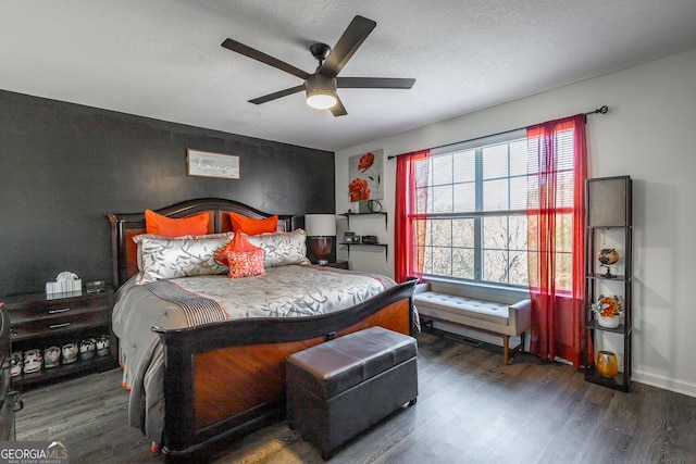 bedroom featuring baseboards, an accent wall, ceiling fan, and wood finished floors