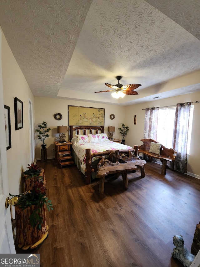 bedroom with a ceiling fan, baseboards, visible vents, dark wood finished floors, and a textured ceiling