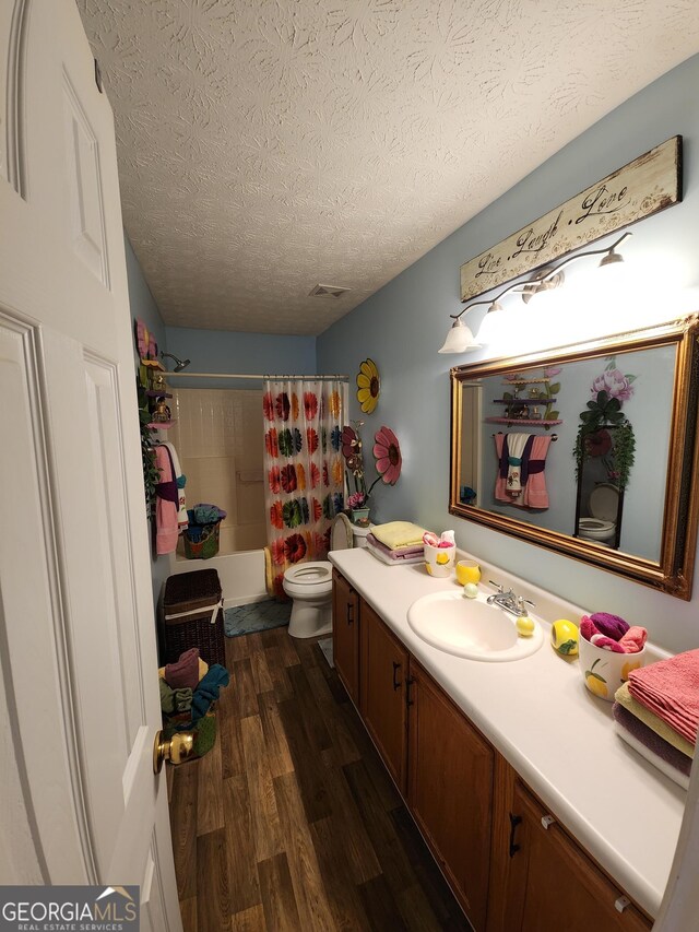 bathroom with toilet, shower / tub combo with curtain, vanity, wood finished floors, and a textured ceiling