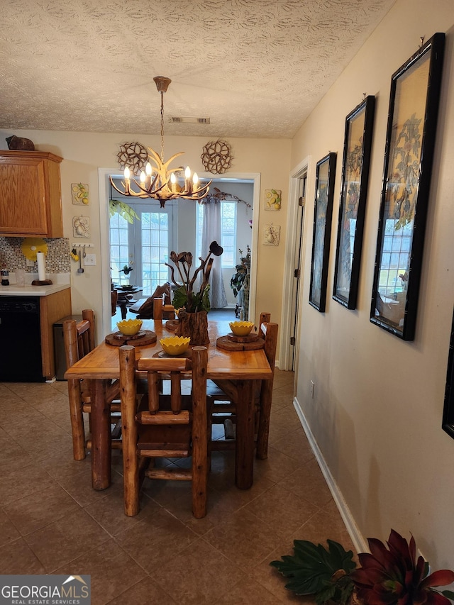 dining room with visible vents, dark tile patterned floors, a textured ceiling, baseboards, and a chandelier