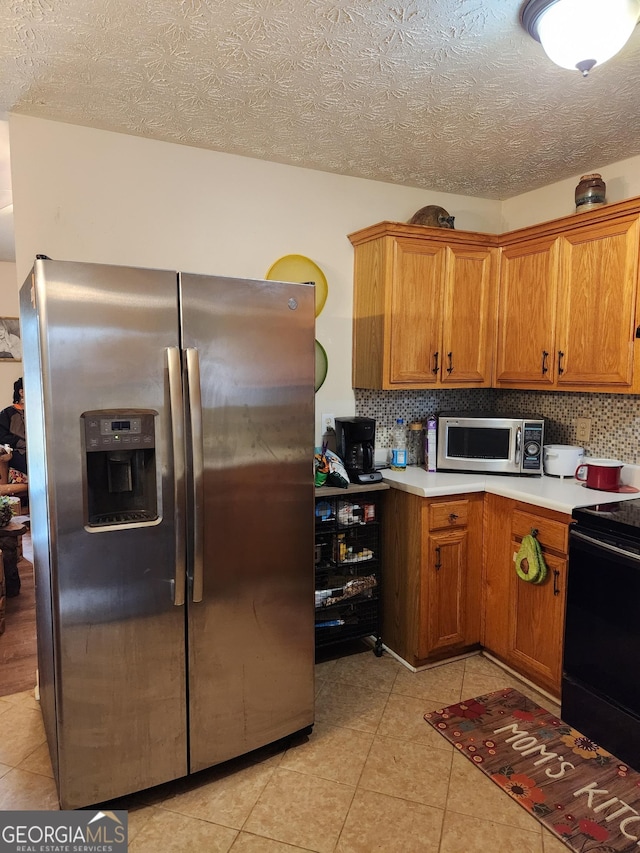 kitchen featuring stainless steel appliances, backsplash, brown cabinetry, and light countertops