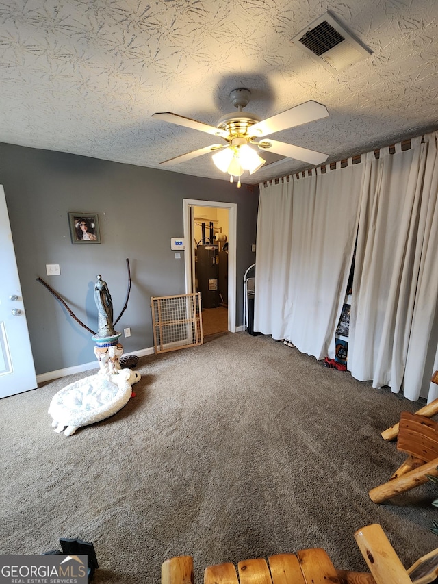 miscellaneous room featuring a ceiling fan, baseboards, visible vents, carpet floors, and a textured ceiling