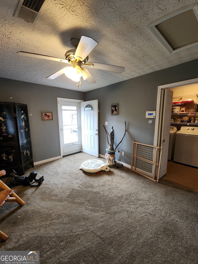 miscellaneous room featuring visible vents, washer and clothes dryer, a textured ceiling, carpet flooring, and baseboards