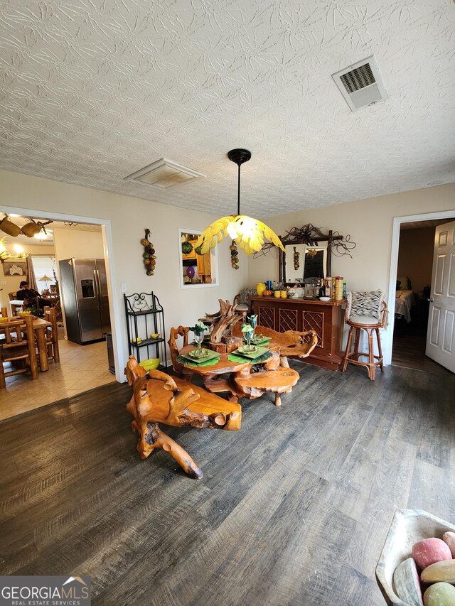 dining space featuring visible vents, a textured ceiling, and wood finished floors