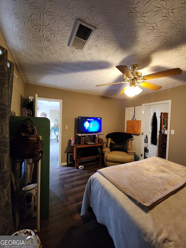 bedroom with ceiling fan, visible vents, a textured ceiling, and dark wood-style floors