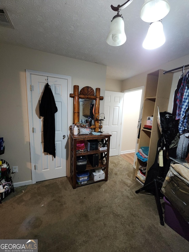 carpeted bedroom with visible vents, baseboards, and a textured ceiling