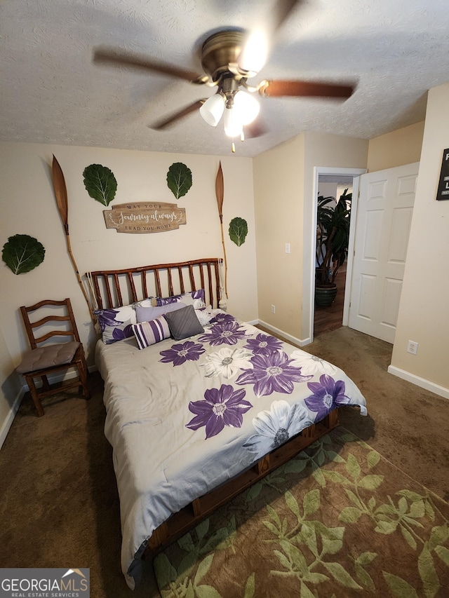 carpeted bedroom featuring a spacious closet, a textured ceiling, baseboards, and a ceiling fan