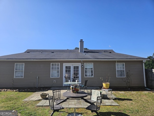 back of house with fence, a lawn, french doors, a chimney, and a patio