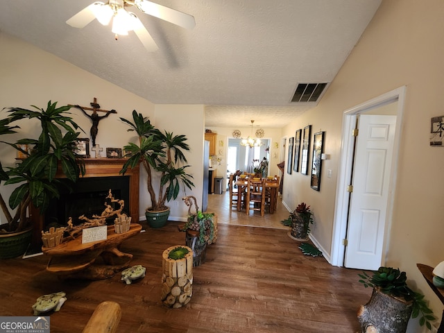 living area featuring visible vents, baseboards, a fireplace, wood finished floors, and a textured ceiling