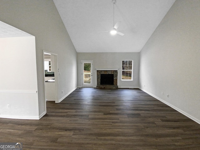 unfurnished living room featuring high vaulted ceiling, dark wood-type flooring, a ceiling fan, a fireplace, and baseboards