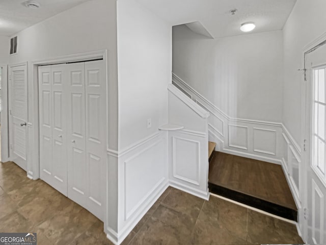 hallway featuring stairs, a wainscoted wall, a decorative wall, and visible vents