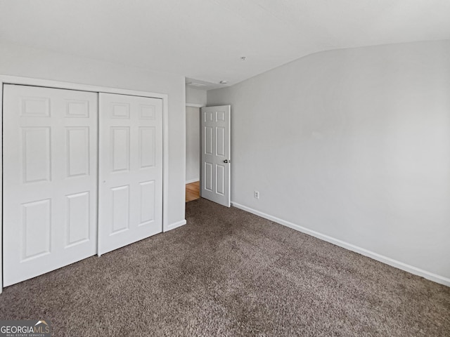 unfurnished bedroom with vaulted ceiling, baseboards, a closet, and carpet floors