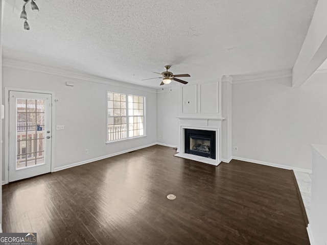 unfurnished living room featuring dark wood finished floors, a fireplace, a textured ceiling, and a wealth of natural light