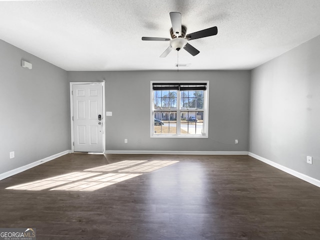 empty room featuring baseboards, dark wood-type flooring, ceiling fan, and a textured ceiling