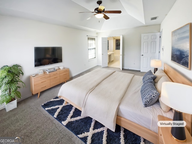 bedroom featuring visible vents, a raised ceiling, connected bathroom, carpet floors, and baseboards