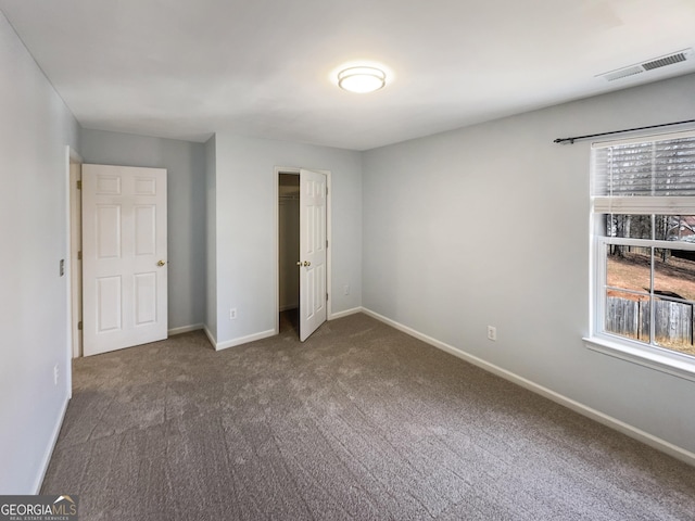 unfurnished bedroom featuring carpet flooring, multiple windows, baseboards, and visible vents