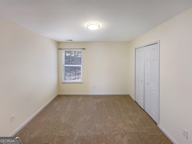 unfurnished bedroom with visible vents, carpet floors, baseboards, and a closet