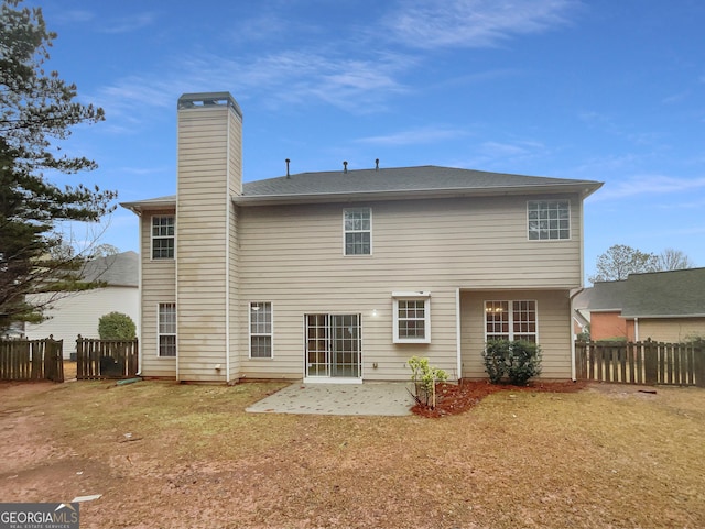 rear view of property with a lawn, a patio area, fence, and a chimney