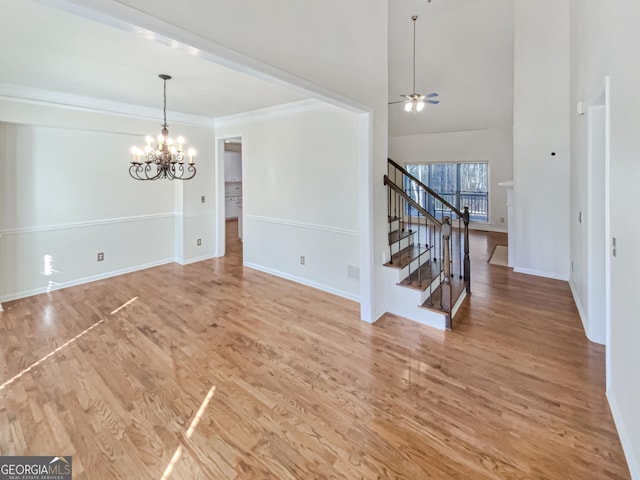unfurnished dining area with light wood-type flooring, baseboards, stairs, and ceiling fan with notable chandelier