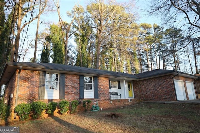 ranch-style home featuring a front lawn, an attached garage, and brick siding