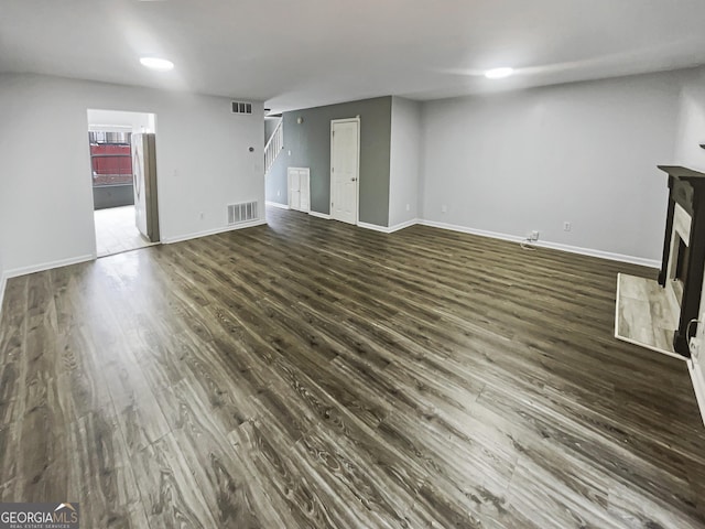 unfurnished living room featuring dark wood finished floors, a fireplace, visible vents, and baseboards