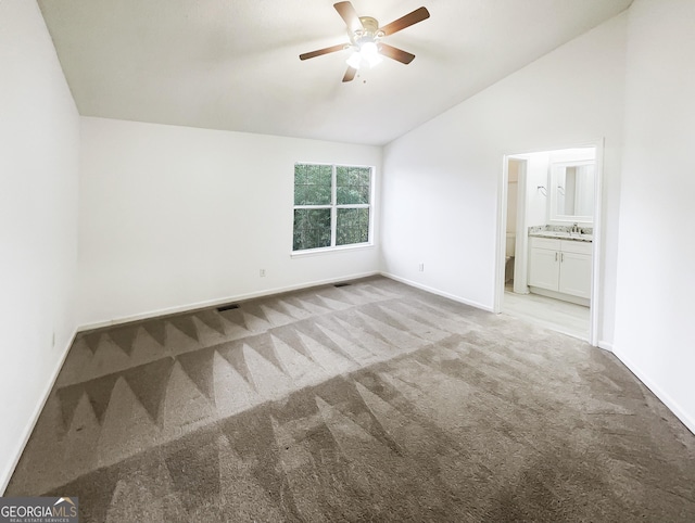 spare room with a ceiling fan, baseboards, a sink, vaulted ceiling, and light colored carpet