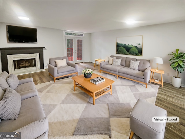 living area with french doors, a fireplace, baseboards, and wood finished floors