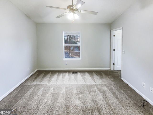 empty room with visible vents, carpet flooring, a ceiling fan, and baseboards