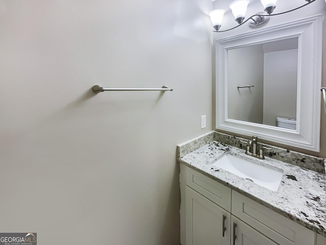 half bath with a notable chandelier, toilet, and vanity