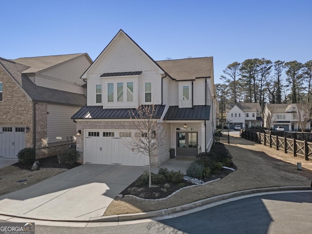 view of front facade with fence, a standing seam roof, concrete driveway, french doors, and a garage