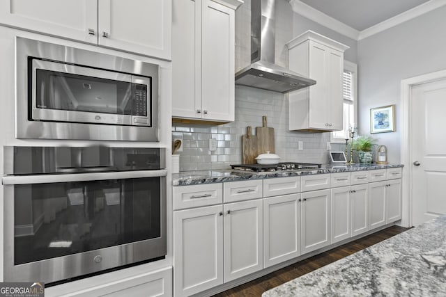 kitchen with crown molding, wall chimney exhaust hood, stone countertops, and stainless steel appliances