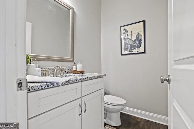 bathroom with vanity, toilet, wood finished floors, and baseboards