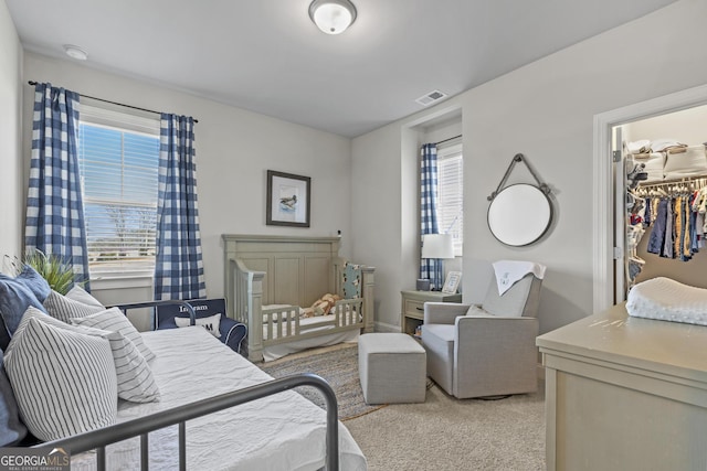 bedroom with a spacious closet, visible vents, and light carpet