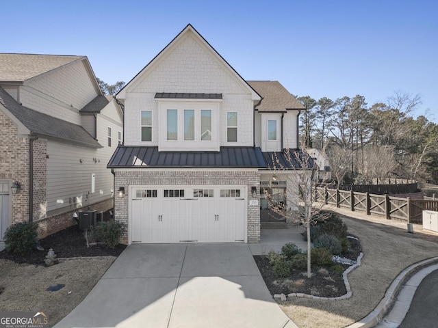 view of front of property with a standing seam roof, an attached garage, concrete driveway, central air condition unit, and brick siding