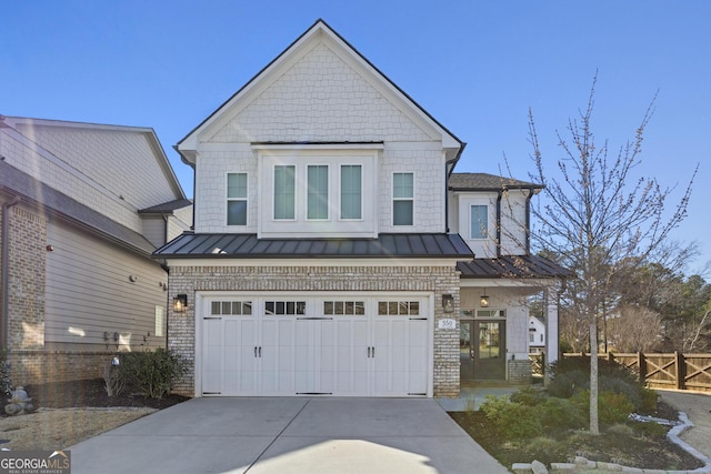 view of front of house with an attached garage, fence, metal roof, driveway, and a standing seam roof