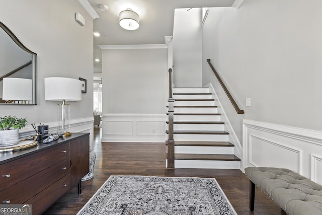 staircase with a decorative wall, wainscoting, crown molding, and wood finished floors