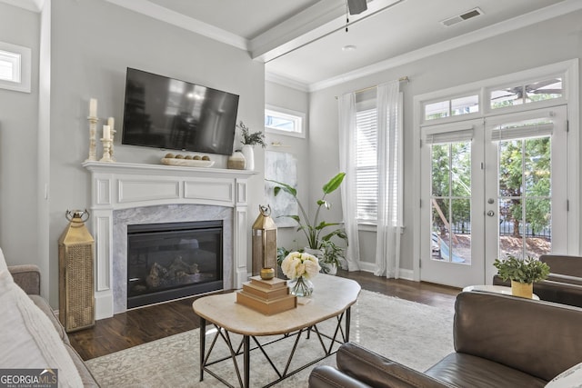 living area featuring wood finished floors, visible vents, a fireplace, french doors, and crown molding