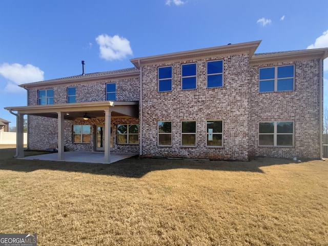 rear view of property featuring a yard, brick siding, and a patio area