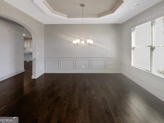 unfurnished dining area featuring a tray ceiling, arched walkways, dark wood-style flooring, a sink, and a chandelier